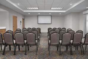 A conference room with rows of chairs, a projector screen, and a carpeted floor. - Hampton Inn & Suites Lake City (Lake City)