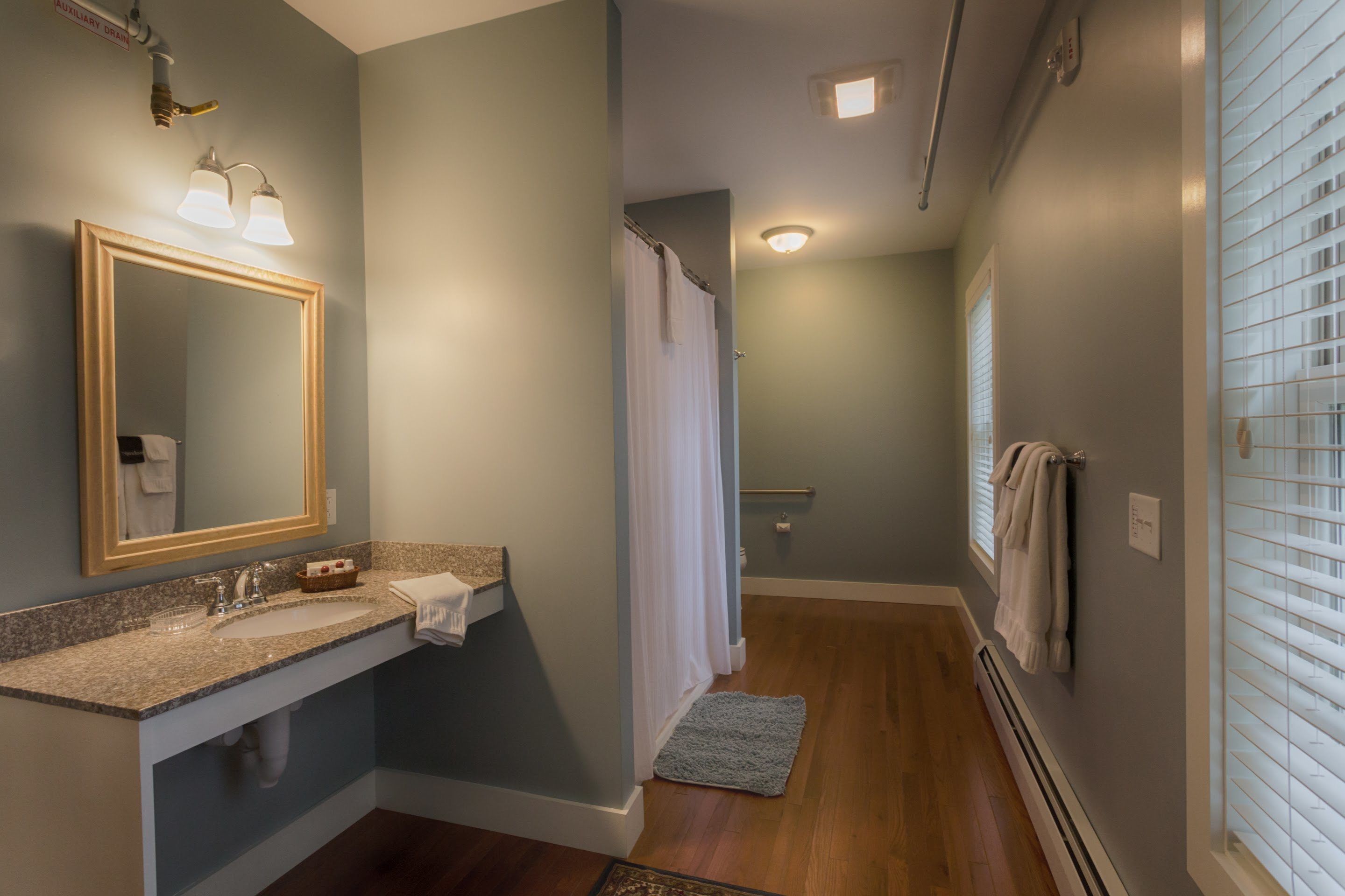 A bathroom with a sink, mirror, and shower.