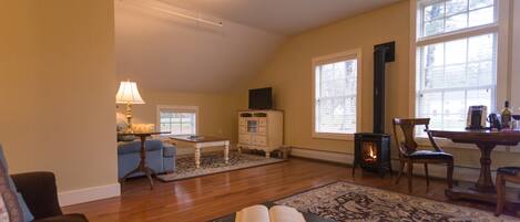 A cozy living room with a fireplace, a sofa, a coffee table, and a bookshelf.