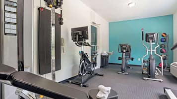 Un gimnasio con una banca, bicicletas estáticas y diverso equipo de ejercicio.