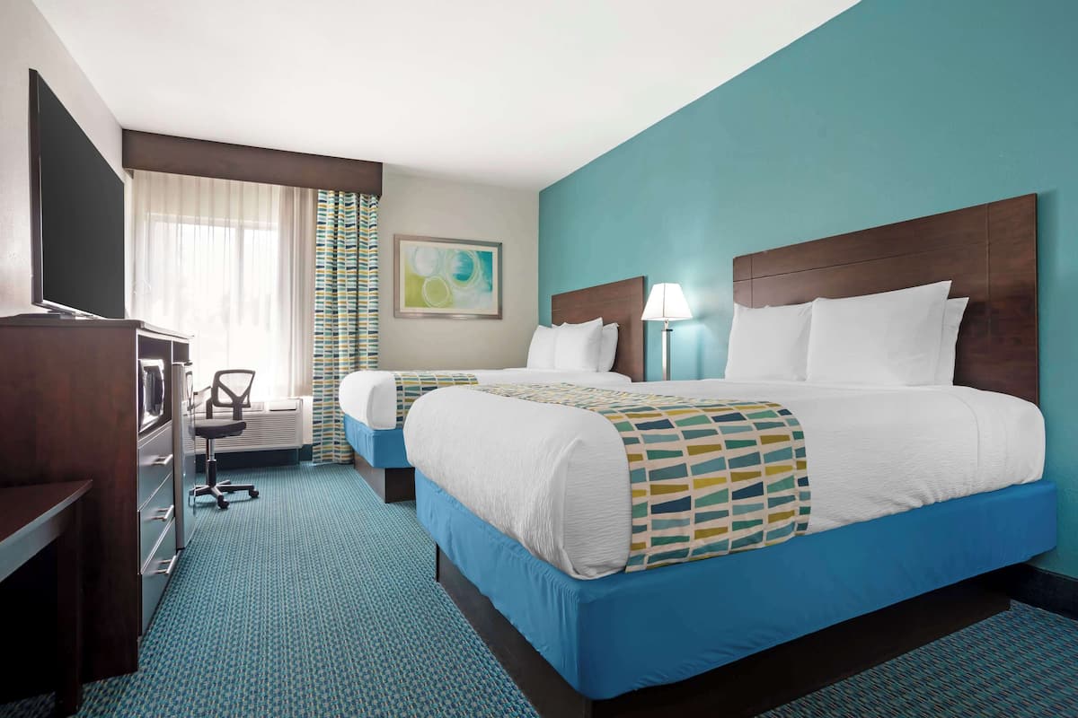 A hotel room with a large bed, a desk, a chair, and a television.