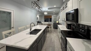 A modern kitchen with a central island, white cabinetry, and a black stove. - St Croix Inn Solon Springs  (Solon Springs)