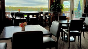 A restaurant with a view of a forest and lake, wooden ceiling, and outdoor seating. - St Croix Inn Solon Springs  (Solon Springs)