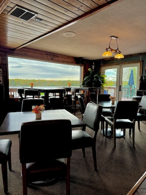 A restaurant with a view of a forest and lake, wooden ceiling, and outdoor seating. - St Croix Inn Solon Springs  (Solon Springs)
