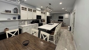 A modern kitchen with white cabinets, a dining table, and a built-in island with a sink. - St Croix Inn Solon Springs  (Solon Springs)