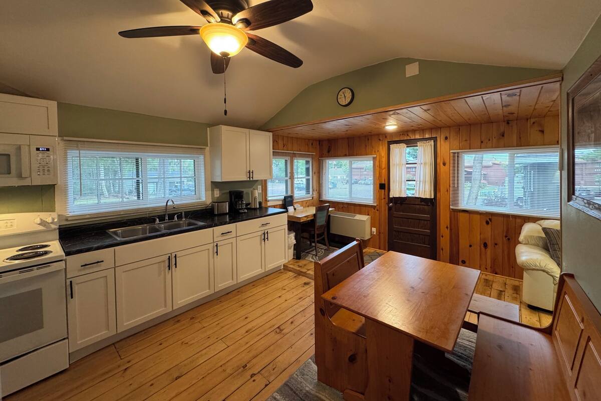 Cozinha com ventilador de teto, micro-ondas, fogão e área de refeições com mesa e cadeiras.
