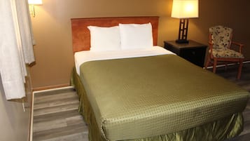 Una habitación de hotel con una cama, una mesita de noche, una silla y una lámpara.