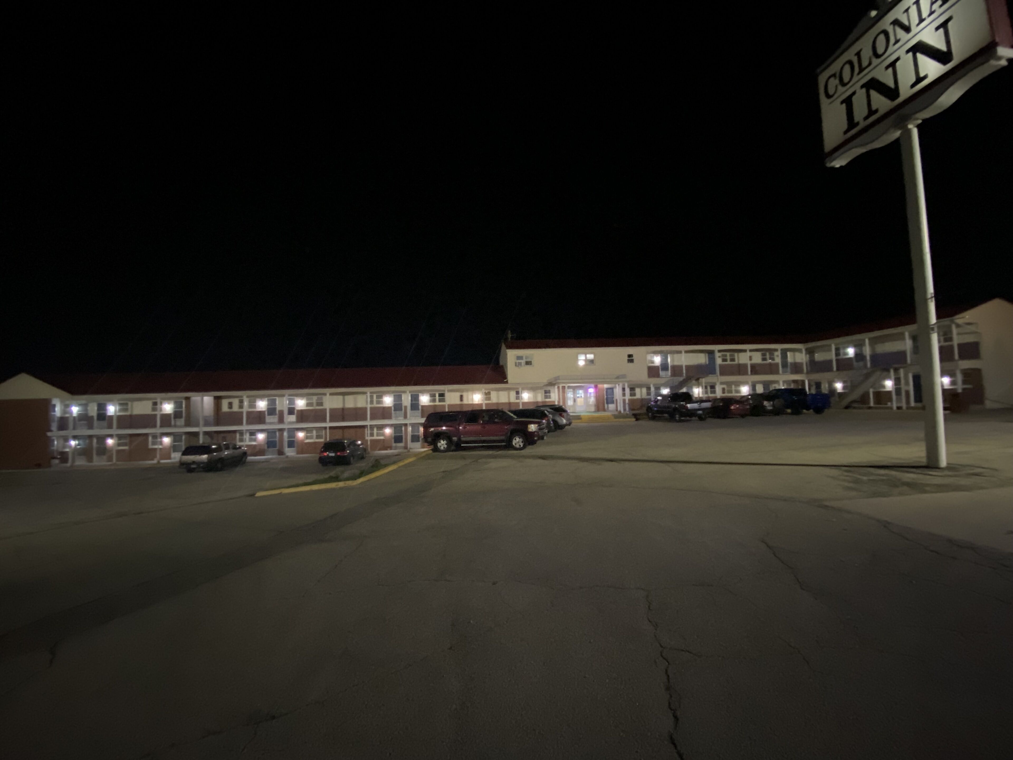 A motel with a sign reading "Colonial Inn" at night.