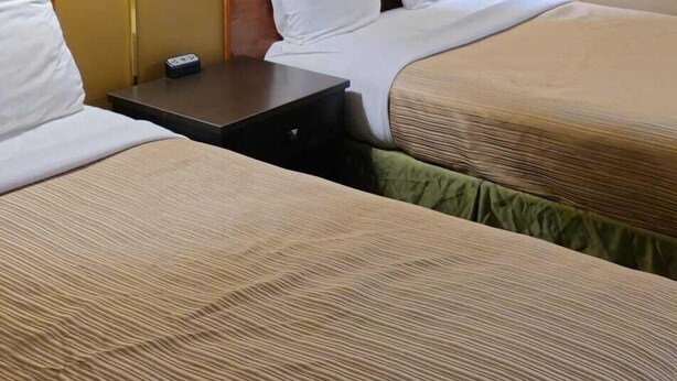Ett hotellrum med två sängar, ett nattduksbord och två väggmonterade lampor.