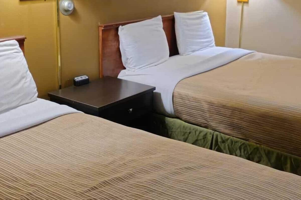 Ein Hotelzimmer mit zwei Betten, einem Nachttisch und zwei Wandlampen.