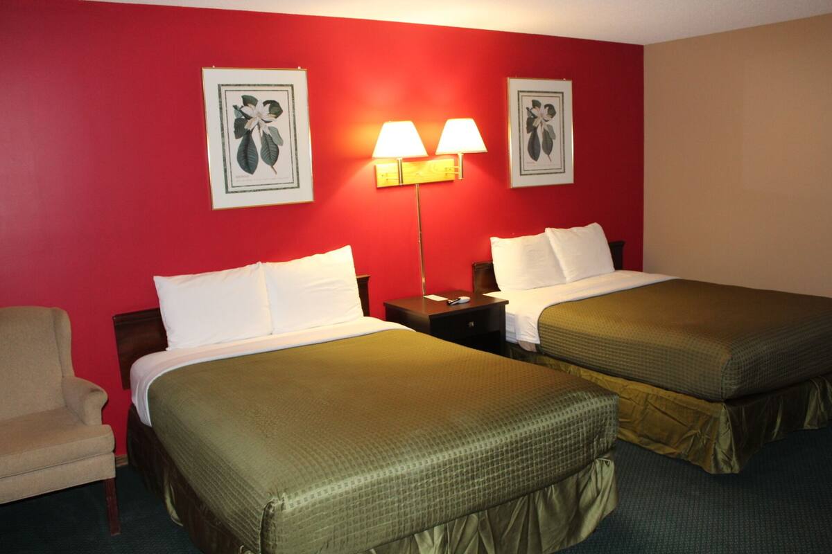 Ein Hotelzimmer mit zwei Betten, einem Sessel und zwei Wandleuchten.