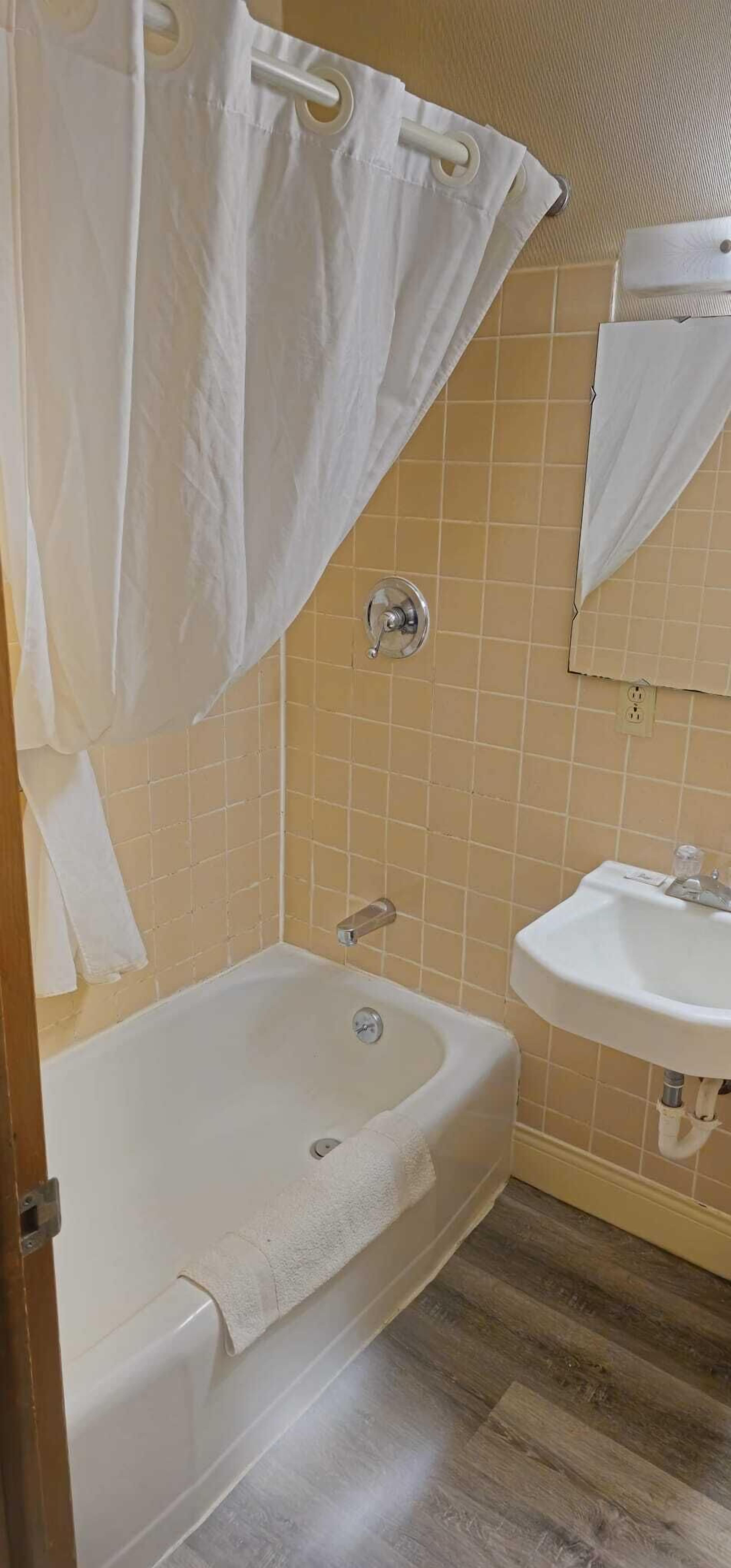 Une salle de bain avec une baignoire, un lavabo et un rideau de douche.