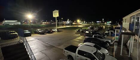Un estacionamiento nocturno con varios vehículos y un letrero que indica Colonial Inn.