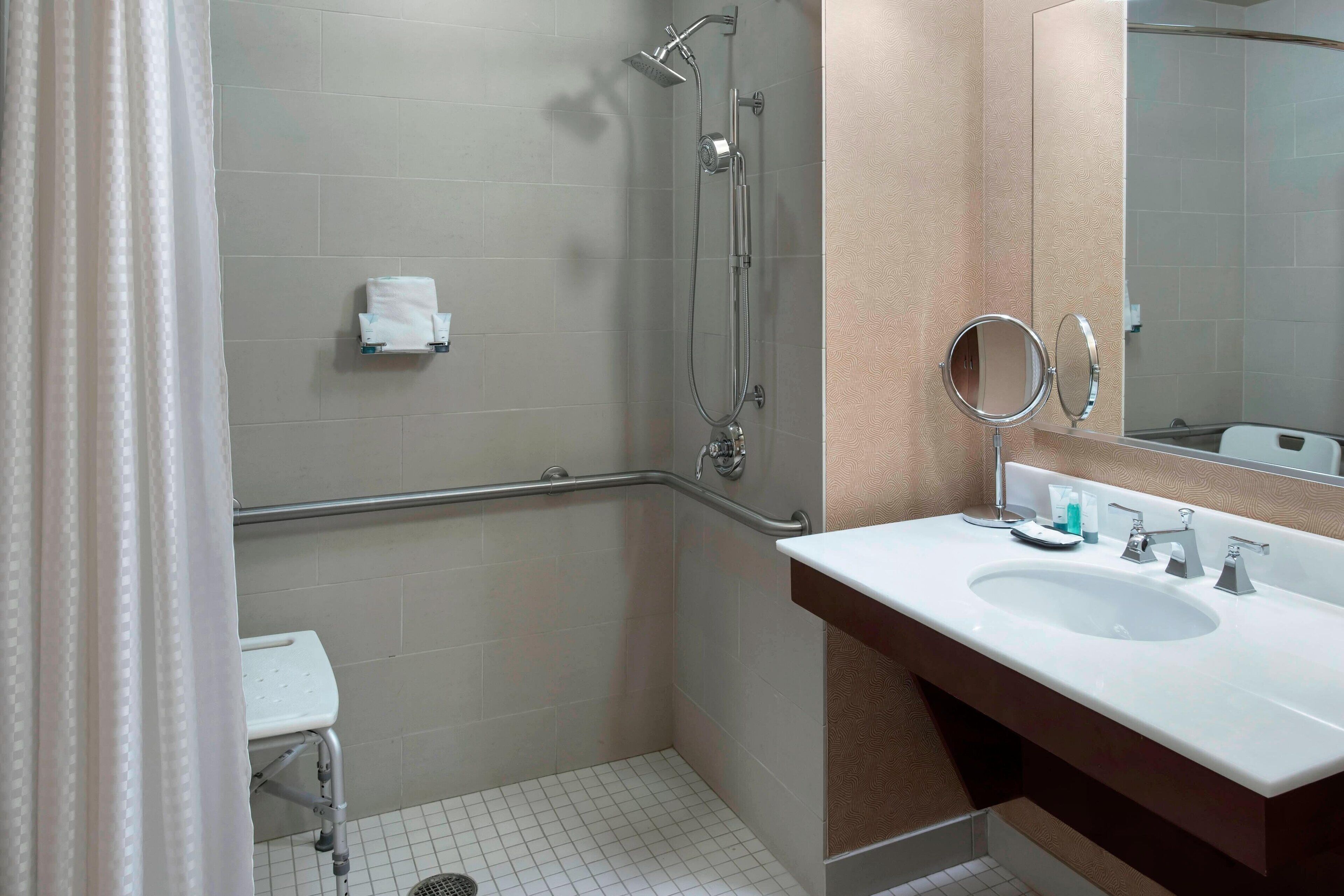 Een badkamer met een douche, wastafel en spiegel.