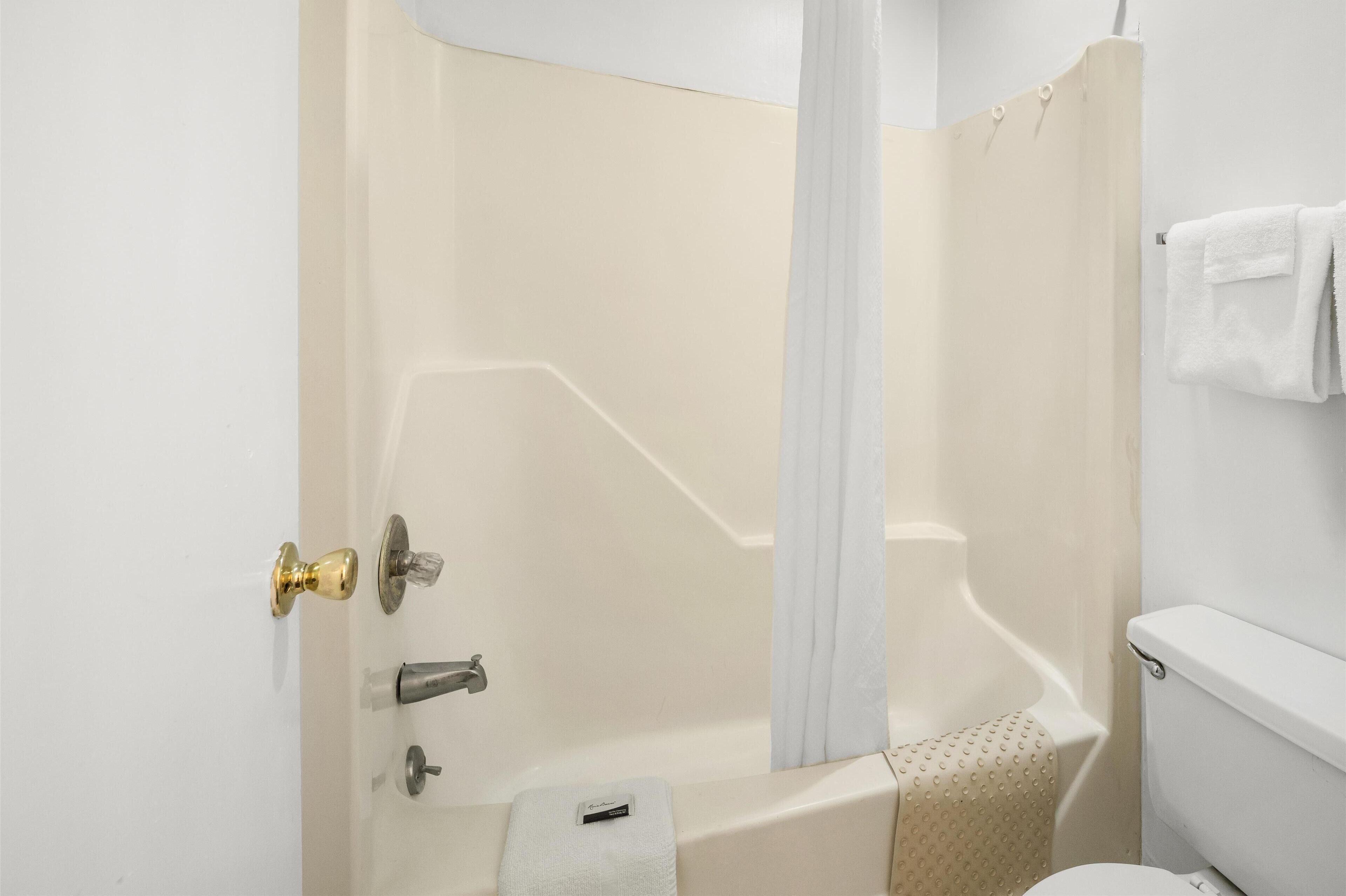Een badkamer met een bad, toilet en douchegordijn.