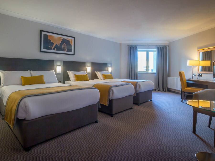 A hotel room with two beds, a desk, a chair, and a television.
