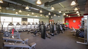 Un gimnasio con cintas de correr, máquinas de pesas y pesas sueltas.