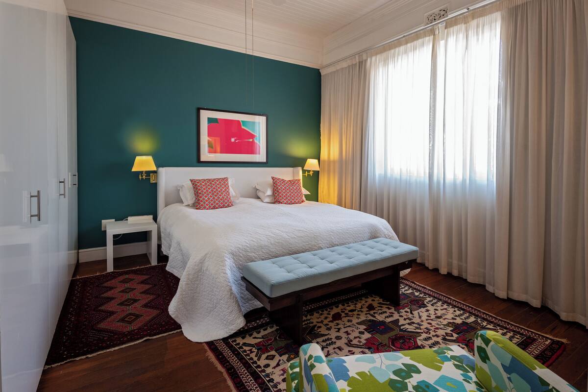 A bedroom with a bed, bedside tables, a bench, and a patterned rug.