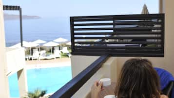 Un balcon avec vue sur une piscine et la mer.