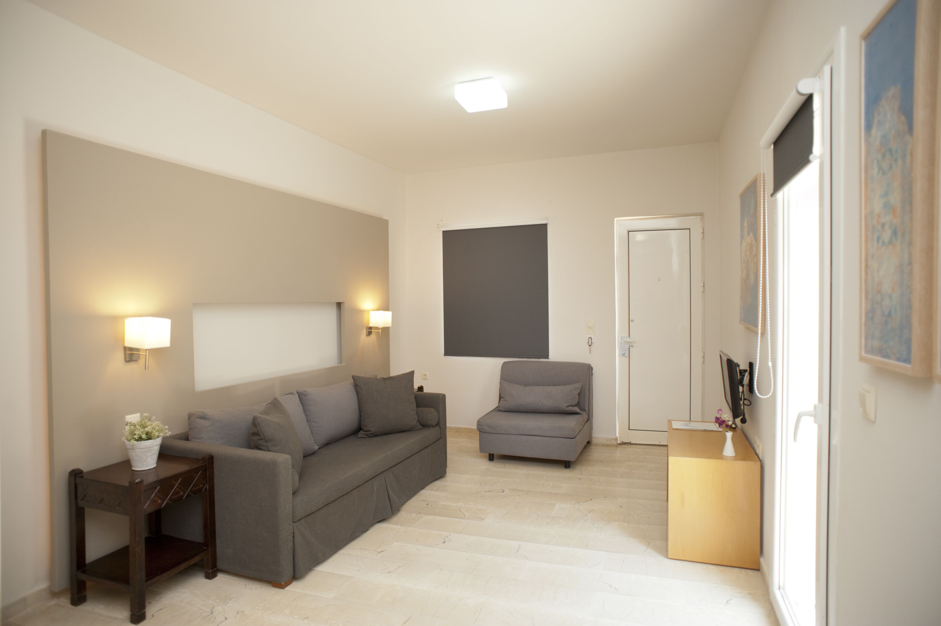 A living room with a sofa, armchair, and a small table with a plant.