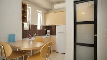 Cocina compacta con comedor, que incluye una pequeña mesa, sillas y un refrigerador.