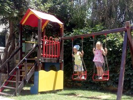Un'area giochi per bambini con altalene e una struttura da arrampicata.