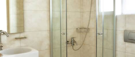 Un baño moderno con ducha de vidrio, lavamanos con toalla y retrete.