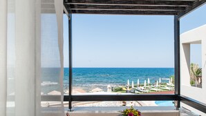 A balcony with a view of the sea, a table with a vase of flowers, and a pool. - Corinna Mare (Chania)