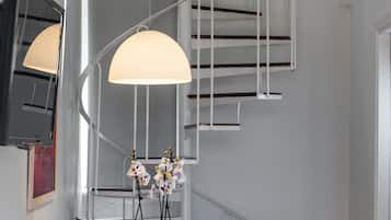 A modern interior with a spiral staircase, a dining table with chairs, and a potted plant.