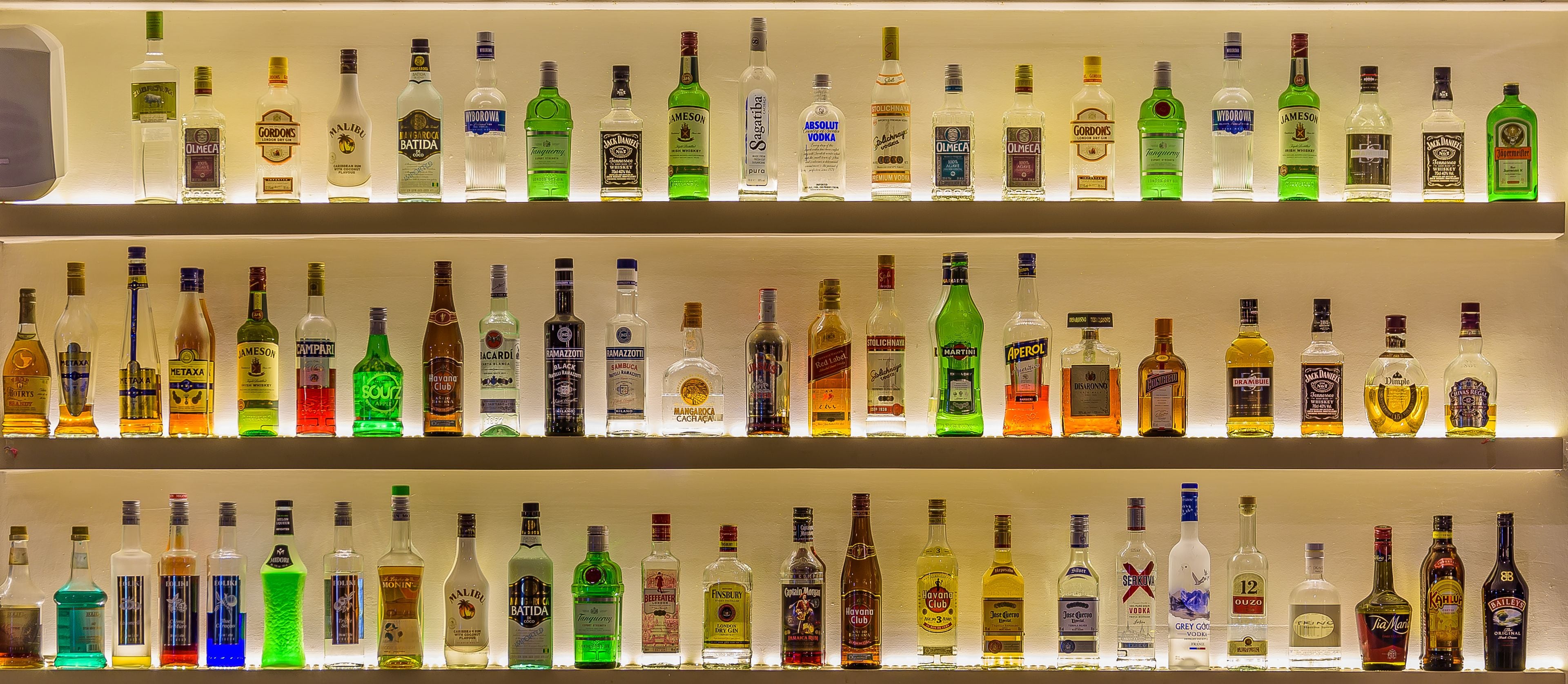 A bar with multiple shelves of various liquor bottles.