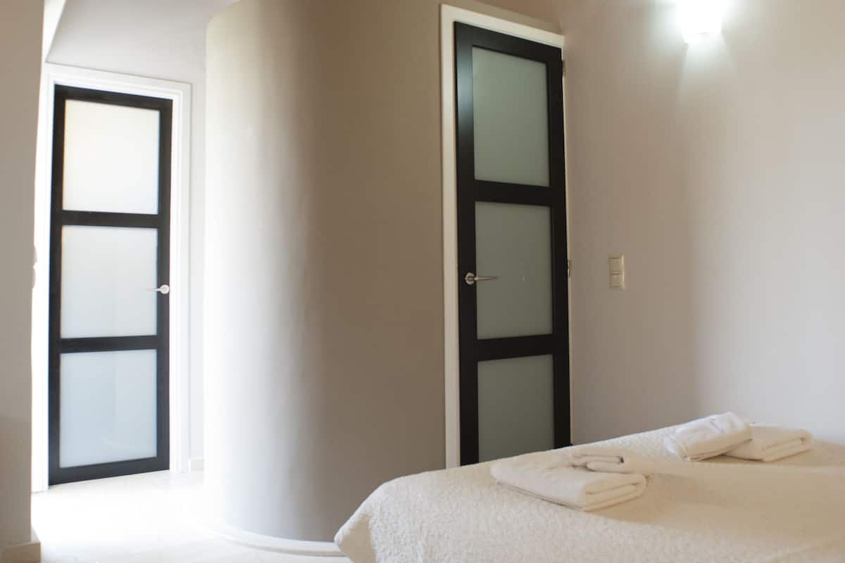 A bedroom with a bed, a door, and a light fixture.