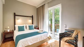 Ein Hotelzimmer mit Bett, Nachttisch, Stuhl und Blick ins Freie.