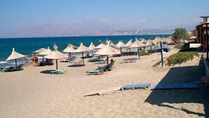 A beach with sun umbrellas, lounge chairs, and a clear view of the sea. - Corinna Mare (Chania)