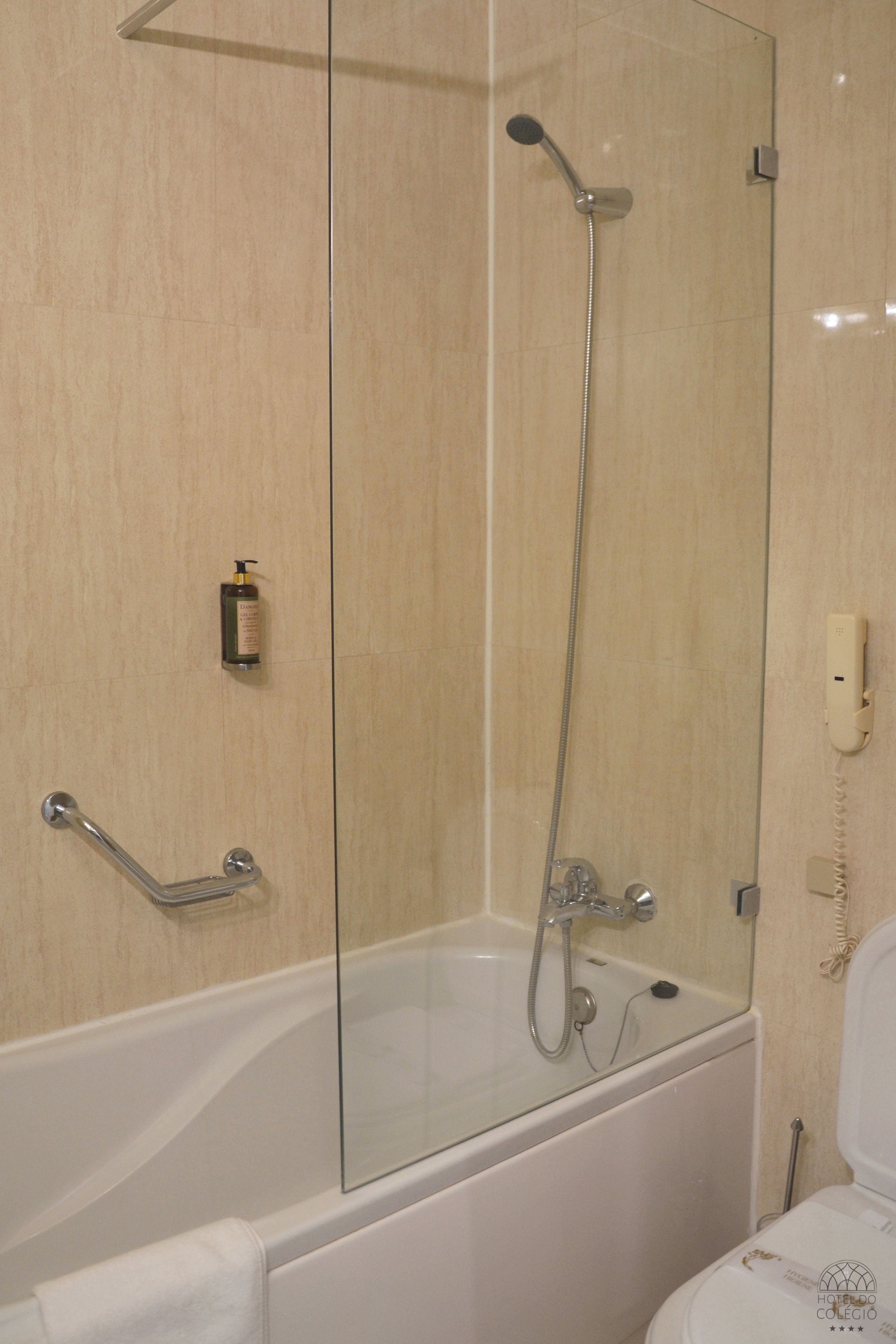 Et moderne badeværelse med en glasafskærmet brusekabine, et hvidt badekar og et toilet.