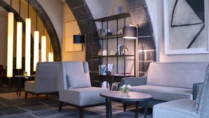 A modern lounge area with two sofas, a round table, and a bookshelf. - Hotel Do Colégio (Ponta Delgada)