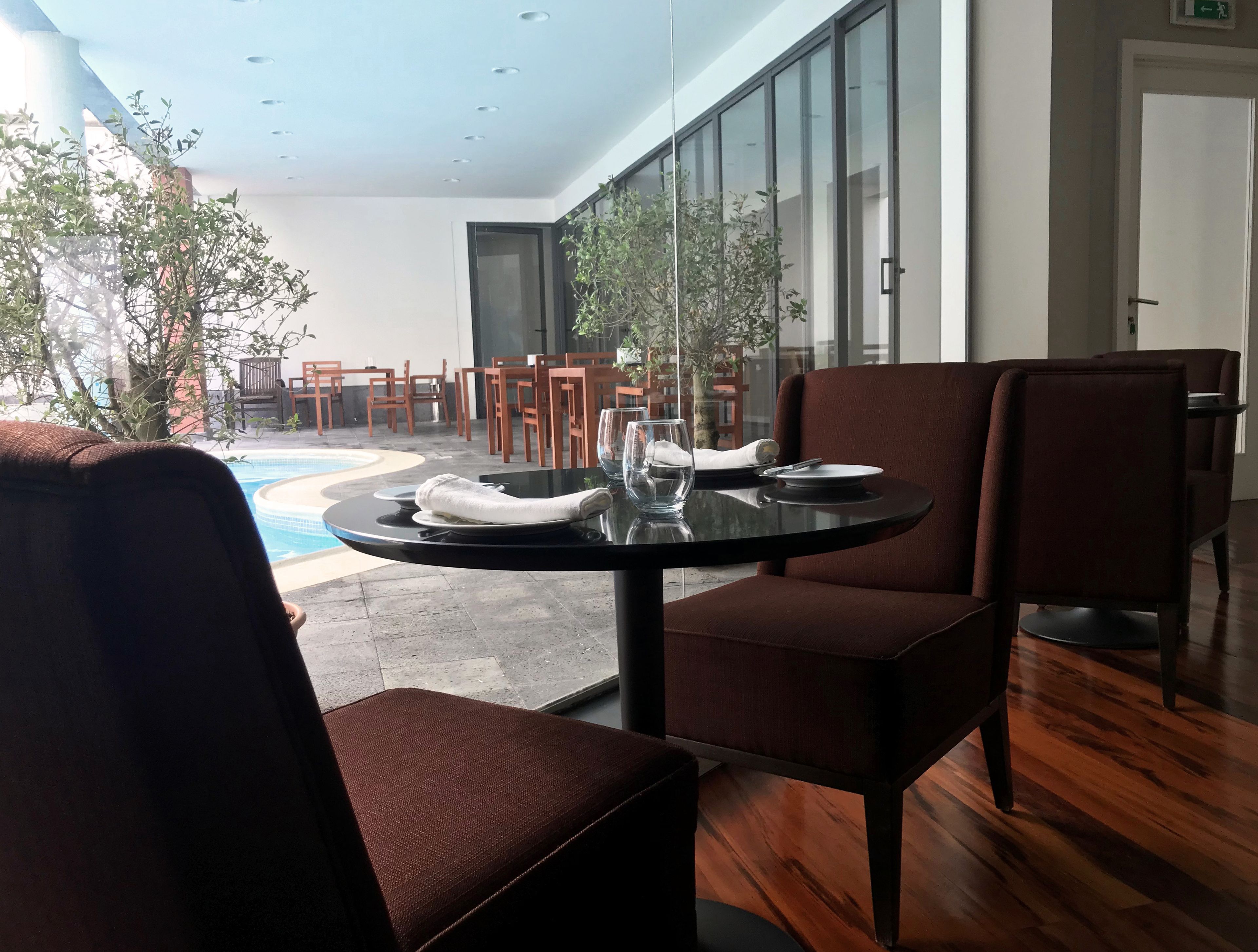 Un coin repas avec une table ronde, des chaises à revêtement marron et une vue sur une piscine extérieure et des chaises de patio.
