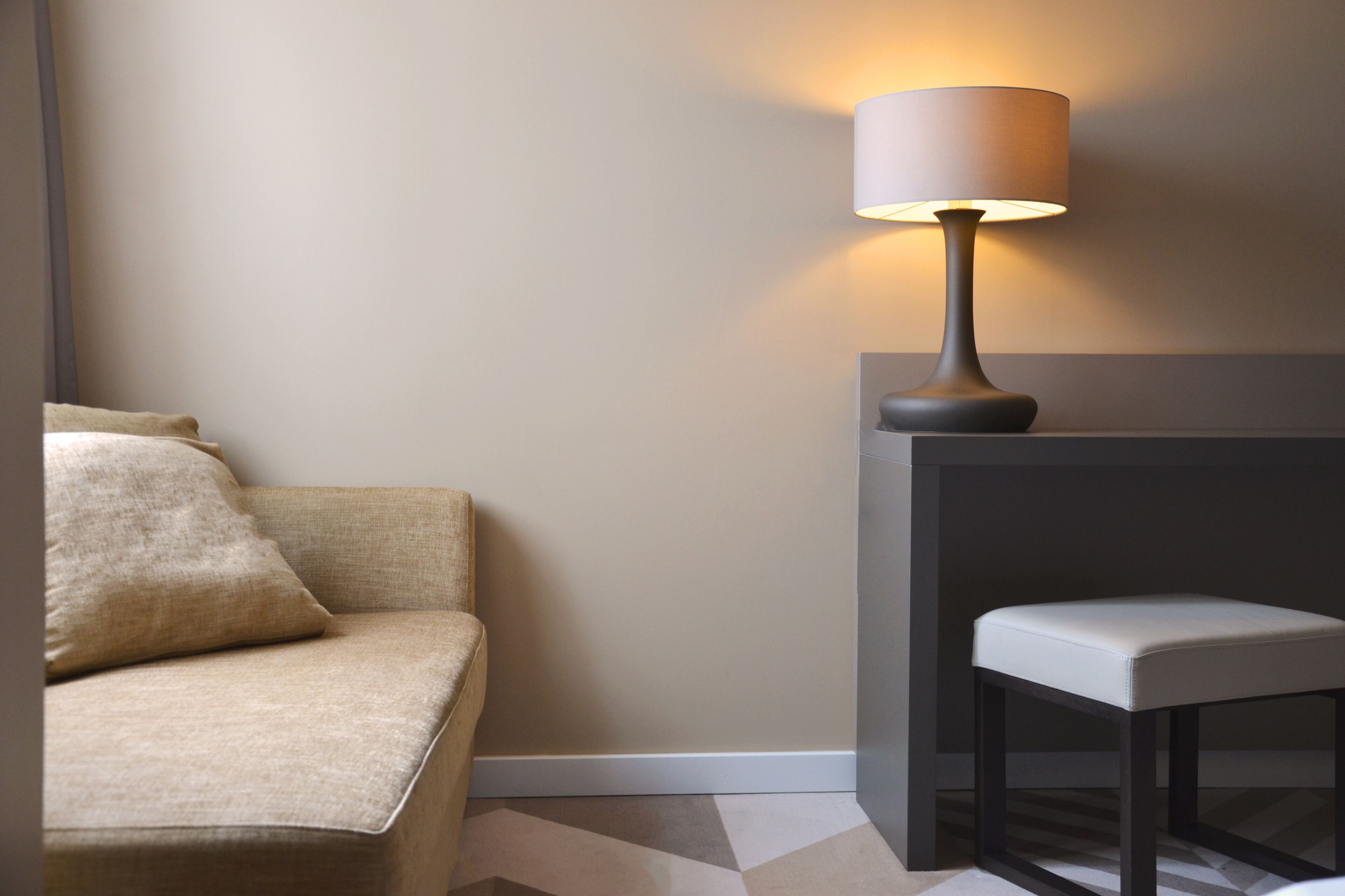 A modern room with a sofa, a small table, and a lamp.