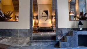 A lobby with a stone staircase, a reception desk, and a framed abstract artwork. - Hotel Do Colégio (Ponta Delgada)