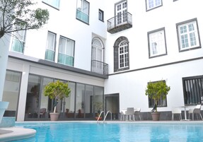 Una piscina al aire libre, sillones reclinables de piscina