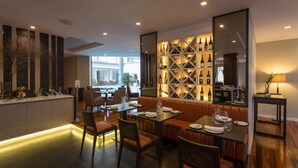 A modern restaurant with a central seating area, a wine display, and a view of the street. - Hotel Do Colégio (Ponta Delgada)
