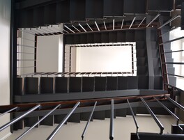 Una escalera moderna con barandillas de metal y peldaños de madera.