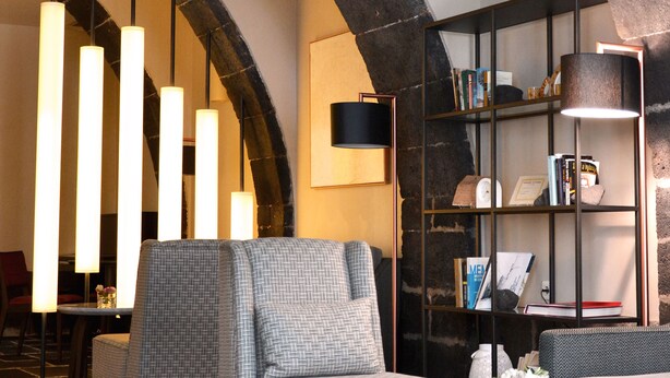 A cozy lounge area with a stone archway, modern furniture, and a bookshelf. - Hotel Do Colégio (Ponta Delgada)