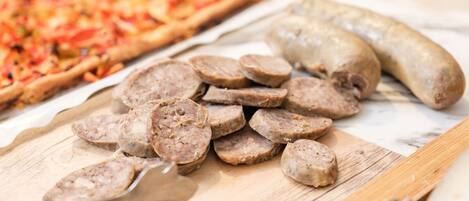 Sliced sausages and a pizza on a wooden board.