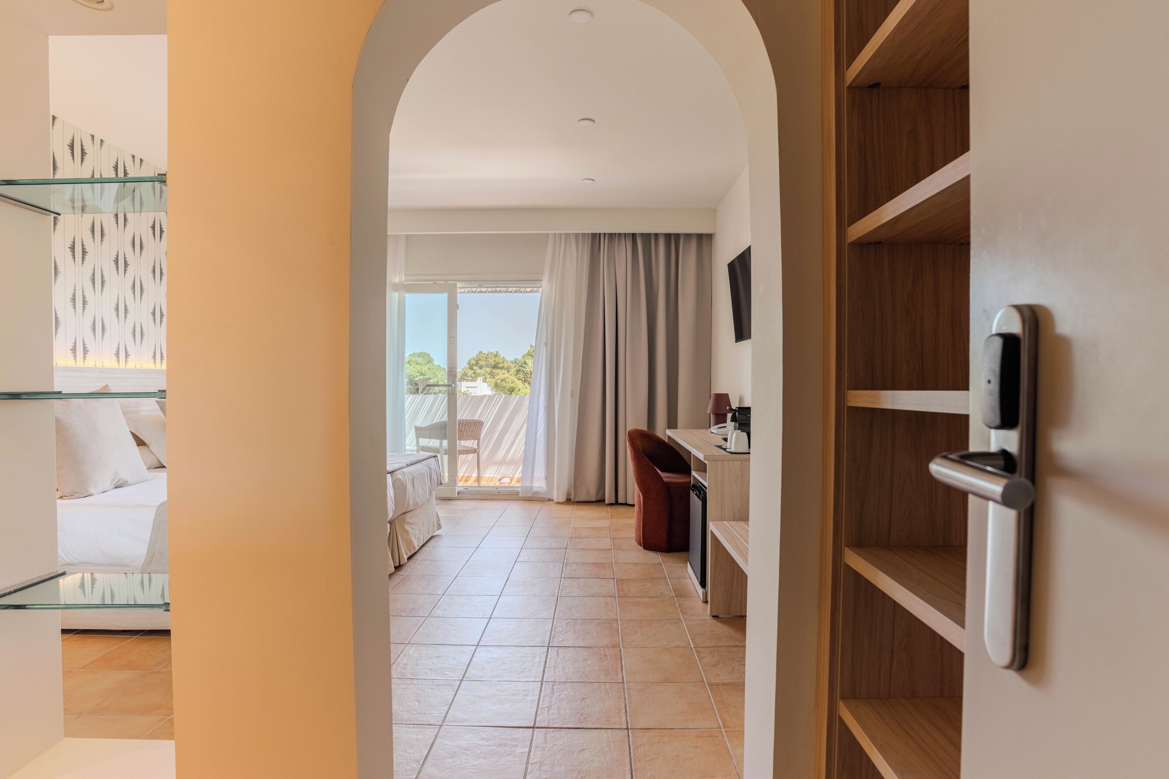 Une chambre d’hôtel avec un balcon, un bureau et une chaise.