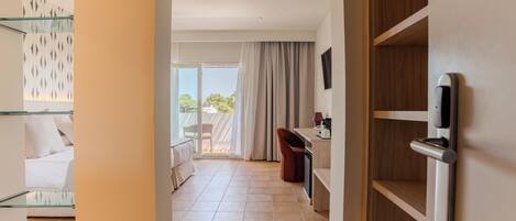 Quarto de hotel com varanda, escrivaninha e cadeira.