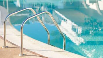 Una piscina al aire libre, sombrillas, tumbonas