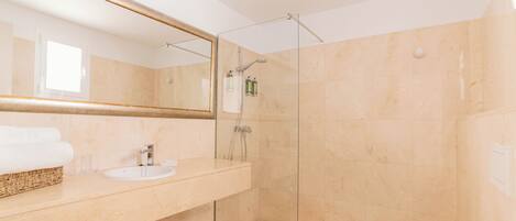 A modern bathroom with a glass-enclosed shower, a sink with a mirror above, and a towel rack.
