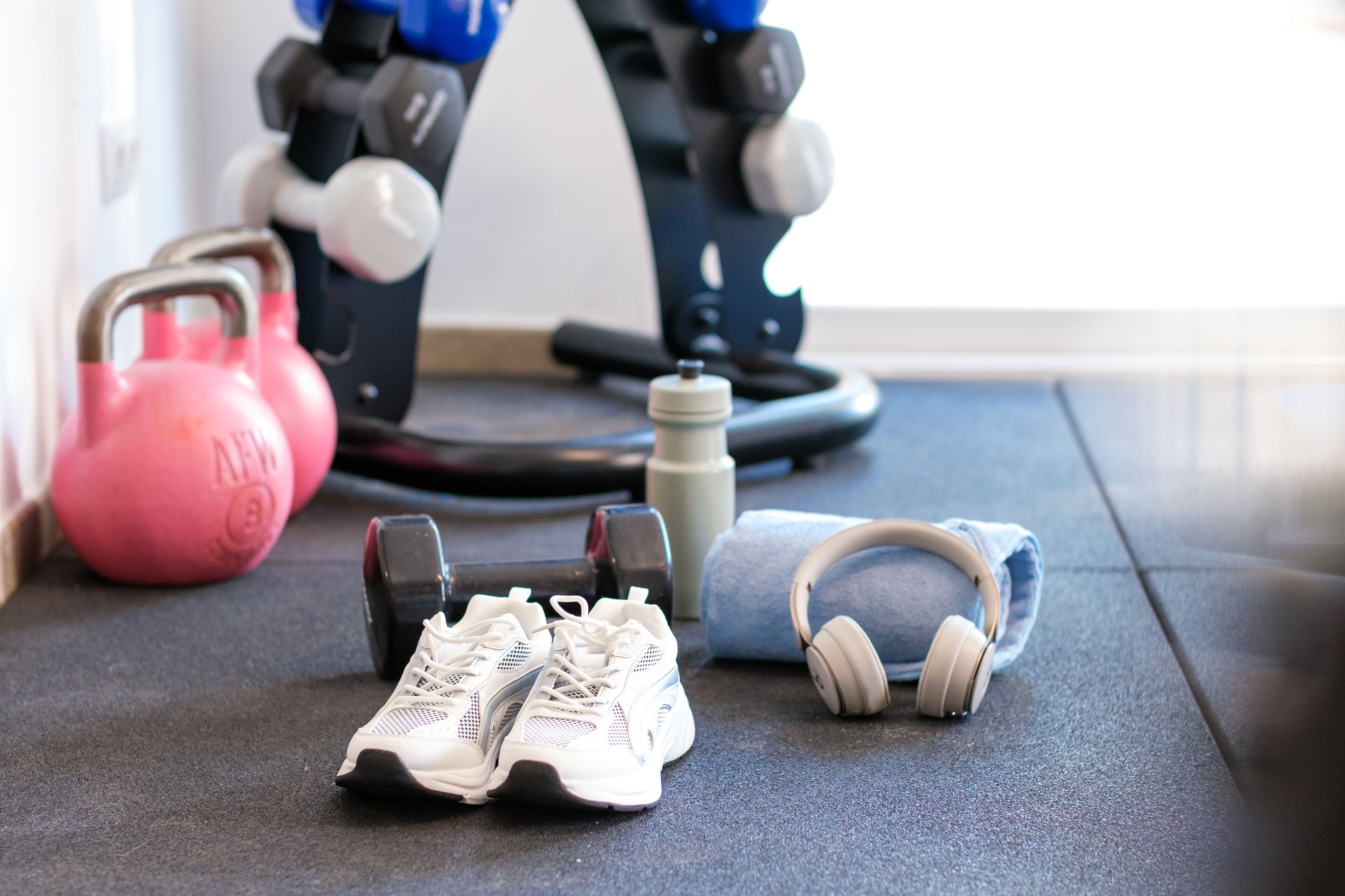 Une salle de sport équipée de matériel d’exercice, notamment des haltères, un kettlebell et une bouteille d’eau.