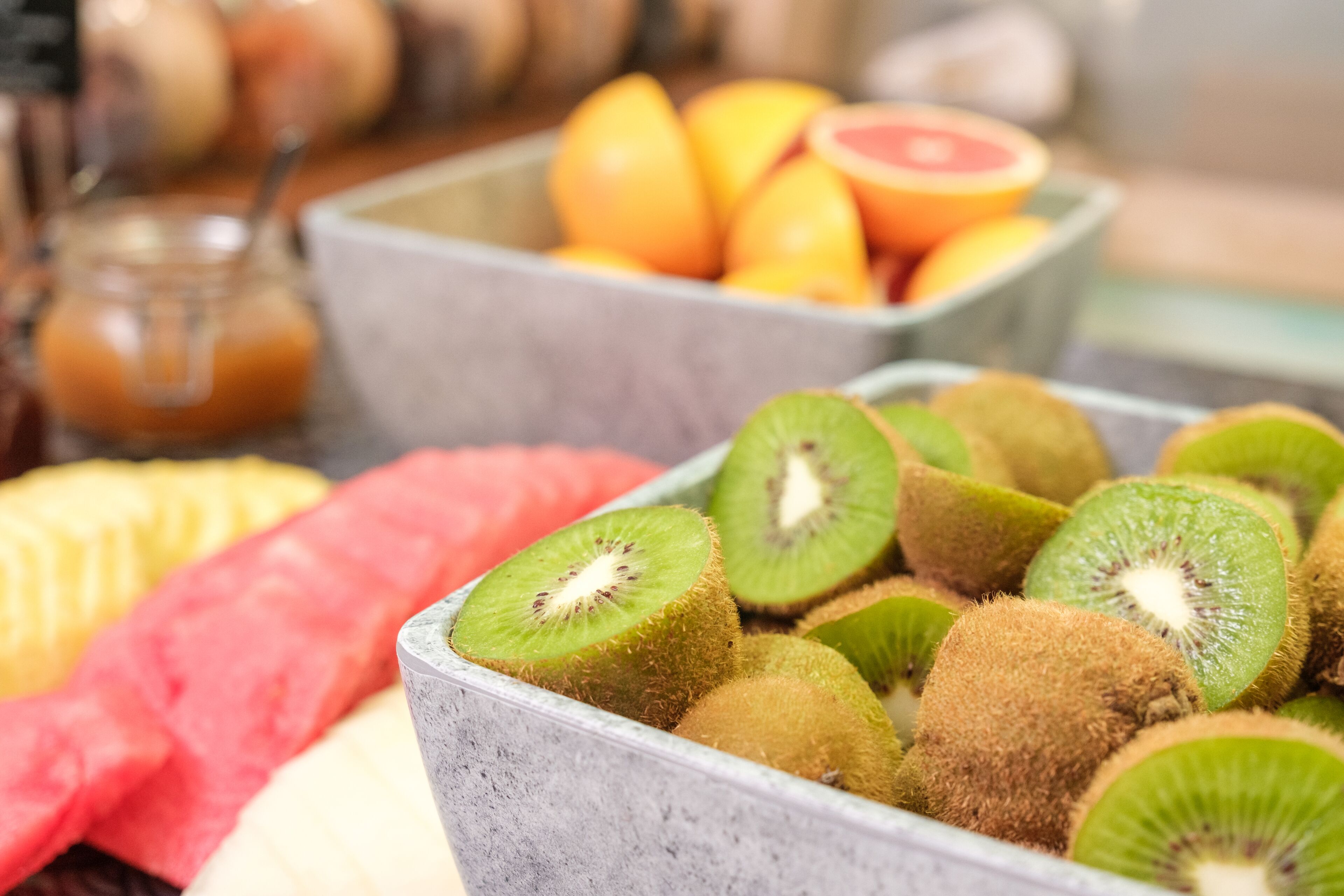 Une variété de fruits frais, notamment des kiwis, des pastèques et des oranges, présentés dans un décor rustique.