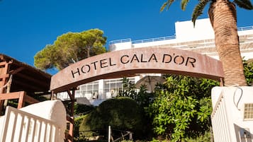 A sign for HOTEL CALA D\u00d6R with a clear view of the building's architecture and surrounding greenery.